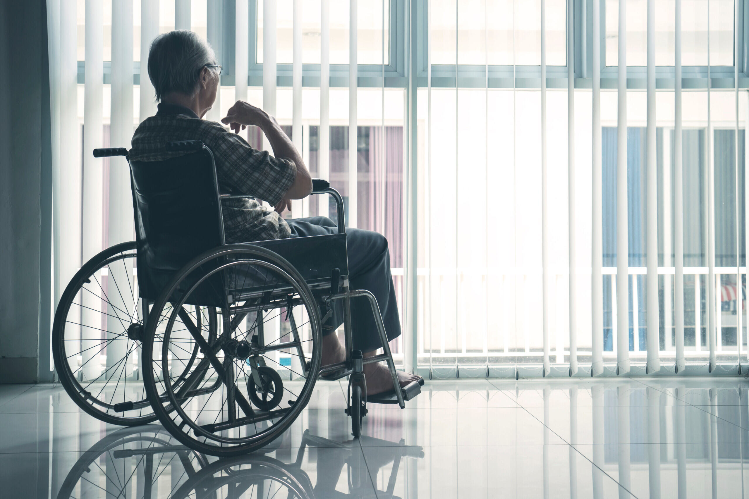Person in wheelchair sitting in front of window.