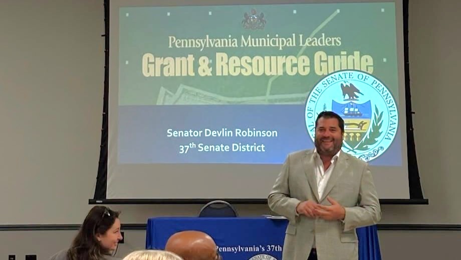 Sen. Robinson speaking to audience in front of screen that says, “Pennsylvania Municipal Leaders Grant & Resource Guide.”