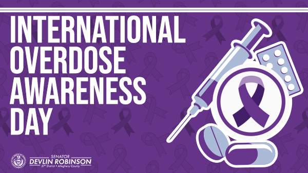 “International Overdose Awareness Day” over a purple ribbon background and a needle and pill icon.